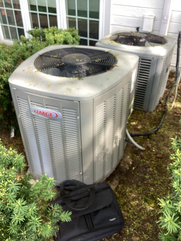 Conducted comprehensive assessment of existing dual HVAC system consisting of two outdoor condenser units showing significant age-related deterioration. Both units exhibited heavy debris accumulation on fan grilles including pollen, leaves, and dirt, along with visible moss and algae growth on concrete pads indicating extended service life. Evaluated the 11-12 year old Lennox condenser unit and secondary unit, noting exterior weathering, compromised cabinet condition, and overall system degradation consistent with equipment nearing end of useful service life. Documented equipment configuration including refrigerant line routing, electrical connections via junction boxes, and current installation positioning against building exterior. Provided detailed replacement estimate based on observed equipment age, declining operational efficiency, and preventive maintenance considerations to avoid potential system failure.