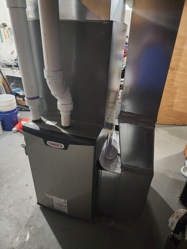 Completed installation of new Lennox high-efficiency furnace in residential basement utility area. Unit was positioned on concrete floor and connected to existing rectangular sheet metal ductwork system with proper sealing and support. White PVC condensate drainage lines were installed and secured with appropriate fittings to ensure proper moisture removal from the system. Yellow gas supply line was connected to furnace per manufacturer specifications and local code requirements. All ductwork connections were completed, including large rectangular supply plenum and flexible ducting to distribution system. Condensate pump assembly was installed at base of unit for proper drainage management. Verified all electrical connections, tested ignition sequence, and confirmed proper airflow through supply and return ducts. System was commissioned and tested for safe operation, with all safety controls functioning as designed.