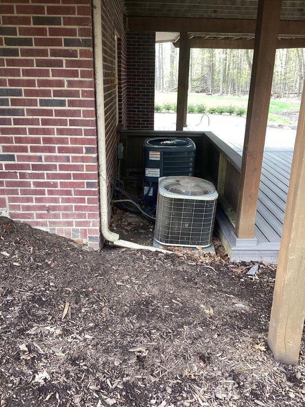 Completed comprehensive estimate for replacement of two R-22 outdoor condenser units and associated indoor air handling equipment. The existing system consists of aging R-22 units located in a recessed alcove beneath a covered porch area, with corresponding indoor equipment housed in the mechanical room including white air handler and supporting infrastructure with PVC condensate drainage routing.