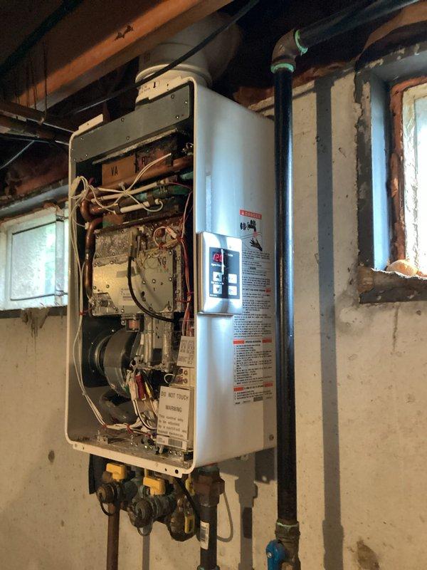 Conducted on-site assessment for tankless water heater replacement in basement utility area. Evaluated existing wall-mounted tankless unit with exposed internal components, including copper piping, gas connections, and electrical wiring. Documented current installation configuration, noting water inlet/outlet connections, venting requirements, and mounting location on concrete wall. Assessed plumbing manifold system with copper and PEX distribution lines, as well as existing valve assembly and water distribution infrastructure to determine compatibility requirements for replacement unit.