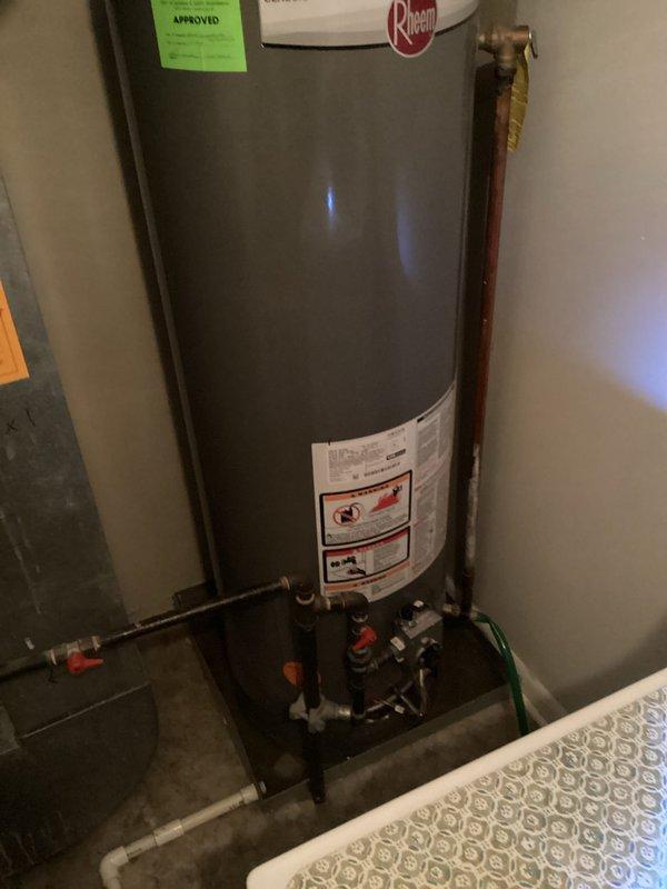 Completed comprehensive assessment and generated estimate for water heater replacement in Building 1, Unit 11-1. Evaluated existing Rheem Classic residential water heater installation including all associated plumbing connections, venting system, and safety components. Documented current configuration showing standard residential setup with copper supply lines, red and blue handled shut-off valves, expansion tank mounted at top of unit, metal venting ductwork, flexible hose connections, and proper drain pan installation at base. Photographed all mechanical connections, safety labels, and existing equipment specifications to provide accurate replacement estimate for client consideration.