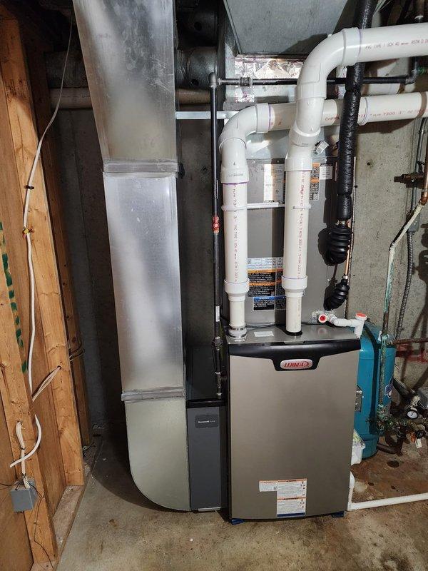 # HVAC System Installation Summary

Successfully completed full residential HVAC system installation including Lennox high-efficiency furnace, air conditioning unit, S40 smart thermostat, and Air Scrubber air purification system.

# Work Performed

Installed new Lennox furnace in basement utility area with proper clearances and mounting on concrete pad. Connected complete PVC venting system with multiple elbows and joints for intake and exhaust, ensuring code-compliant configuration for high-efficiency operation. Installed black flexible ductwork connections to integrate with existing distribution system. Routed and secured vertical supply ductwork along basement framing.

Installed corresponding Lennox air conditioning condenser unit with refrigerant line connections to indoor coil. Completed all electrical connections for both heating and cooling components, ensuring proper voltage and amperage specifications.

Mounted S40 smart thermostat at designated location with proper wiring to