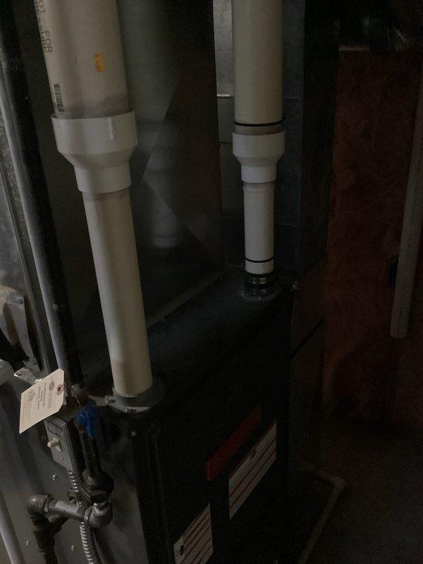 Conducted on-site evaluation for complete air conditioning system replacement. Assessed existing HVAC equipment and mechanical infrastructure in basement utility area, documenting current furnace configuration, PVC condensate drainage system, and associated plumbing connections. Photographed equipment layout including vertical drain lines, coupling assemblies, and existing mechanical room conditions to provide comprehensive replacement estimate specifications.