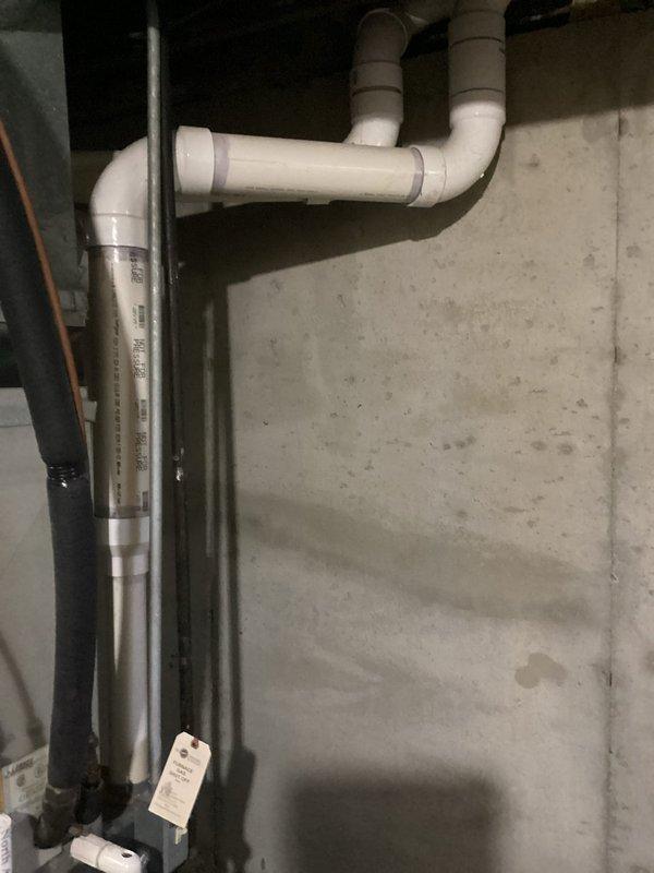 Conducted on-site evaluation for complete air conditioning system replacement. Assessed existing HVAC equipment and mechanical infrastructure in basement utility area, documenting current furnace configuration, PVC condensate drainage system, and associated plumbing connections. Photographed equipment layout including vertical drain lines, coupling assemblies, and existing mechanical room conditions to provide comprehensive replacement estimate specifications.
