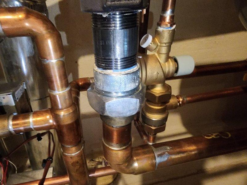 Responded to emergency no-heat call for six-month-old boiler system experiencing dangerously high pressure exceeding 50 psi with active water leakage and visible corrosion on copper piping. Upon arrival, found unit already shut down by customer due to safety concerns. Inspection revealed severe rust and corrosion on multiple copper pipes near the pressure relief system, with pressure gauge confirming excessive system pressure. Identified compromised pressure relief valve and corroded piping as primary failure points requiring immediate attention to prevent potential vessel rupture. Documented extensive corrosion on copper supply lines and fittings, noting unusual degradation for equipment of this age. System was photographed for warranty documentation showing corroded pipes, malfunctioning pressure gauge, and compromised brass fittings throughout the boiler assembly. Recommended immediate replacement of affected components and full system pressure testing before restoration of service 