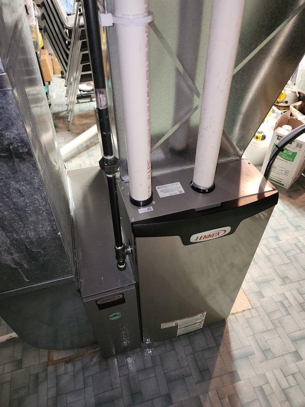 Completed installation of Lennox brand high-efficiency furnace in mechanical room. Connected intake and exhaust venting using white PVC piping routed vertically from unit, along with auxiliary drainage lines. Installed metallic supply ductwork with proper transitions from furnace plenum through attic space, securing all connections and ensuring proper airflow pathways. Unit positioned on tile floor with all manufacturer specifications verified and labeled. System tested and confirmed operational upon completion.