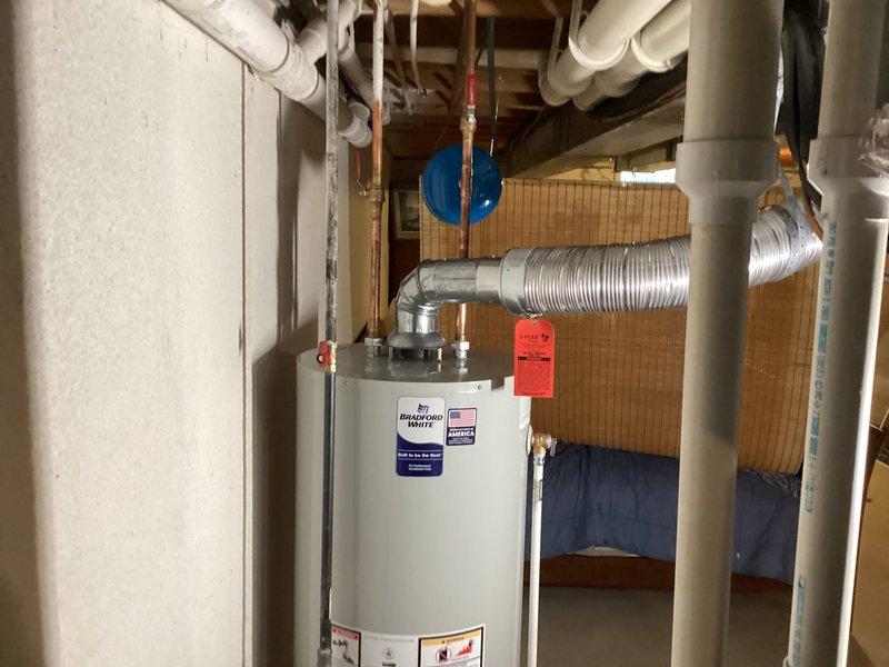 Successfully installed a 50-gallon Bradford White residential water heater in basement mechanical room. Removed existing unit and positioned new water heater in accordance with manufacturer specifications and local plumbing codes. Connected cold water supply line with brass shut-off valve and installed temperature and pressure relief valve with proper discharge piping. Established hot water distribution connections using copper piping with appropriate fittings and isolation valves. Verified all connections for leaks, tested TPR valve operation, and confirmed proper venting configuration. Unit was filled, purged of air, and brought up to operating temperature. System tested and verified functioning correctly with no leaks detected at any connection points.