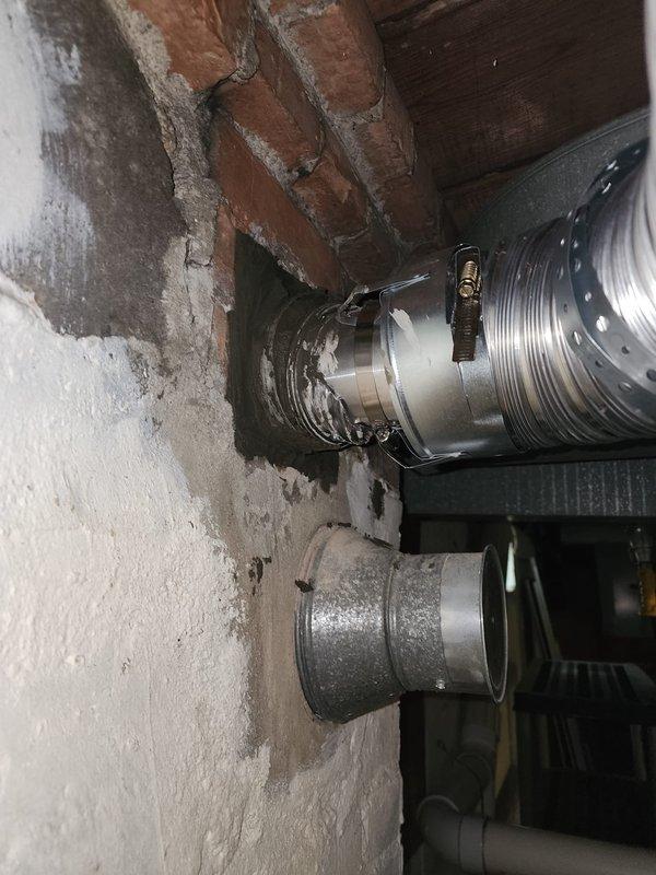 Completed installation of flexible metallic chimney liner in basement utility area, securing ductwork to ceiling structure with proper mounting brackets and connectors. The liner was routed through the existing masonry chimney chase and connected to the HVAC system, ensuring proper ventilation and code compliance. All components were installed and verified for structural integrity and operational functionality.