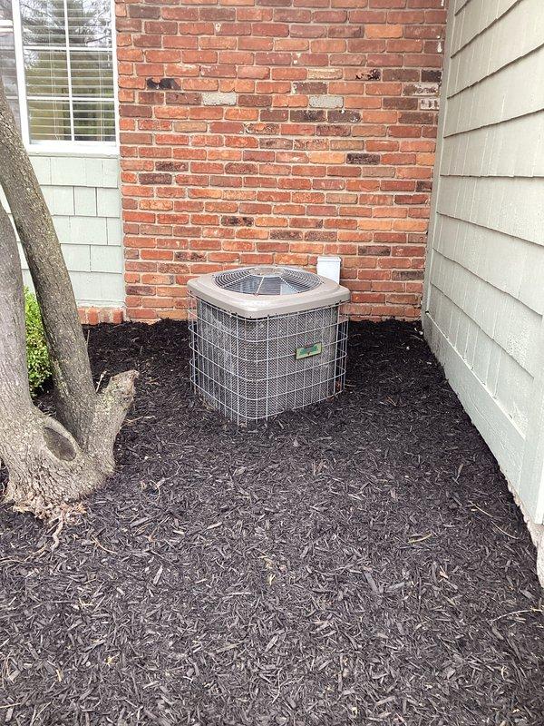 Conducted comprehensive site assessment for commercial HVAC system replacement, documenting existing Carrier furnace installation in interior mechanical space and outdoor condensing unit positioned between building structures. Photographed current equipment configuration, ductwork routing, utility connections including PVC condensate lines and electrical service, and outdoor unit placement in mulched area adjacent to brick exterior wall to develop accurate replacement specifications and installation requirements.