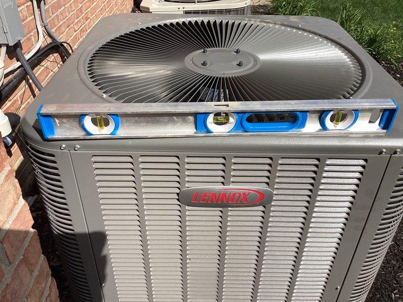 Leveled Lennox air conditioning unit on pad using precision spirit level to ensure proper installation alignment and drainage. Completed comprehensive AC start-up procedure, verifying system operation, refrigerant levels, electrical connections at disconnect box, and airflow through condenser coils. Unit tested and confirmed operational for cooling season.