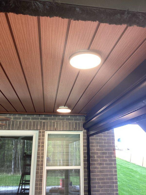 Completed continuation electrical work from previous service call, installing recessed LED lighting fixtures in covered patio ceiling. Installed two round recessed LED lights with bright white output in wood-paneled ceiling area. All fixtures tested and confirmed operational upon completion, with pricing to be provided separately.