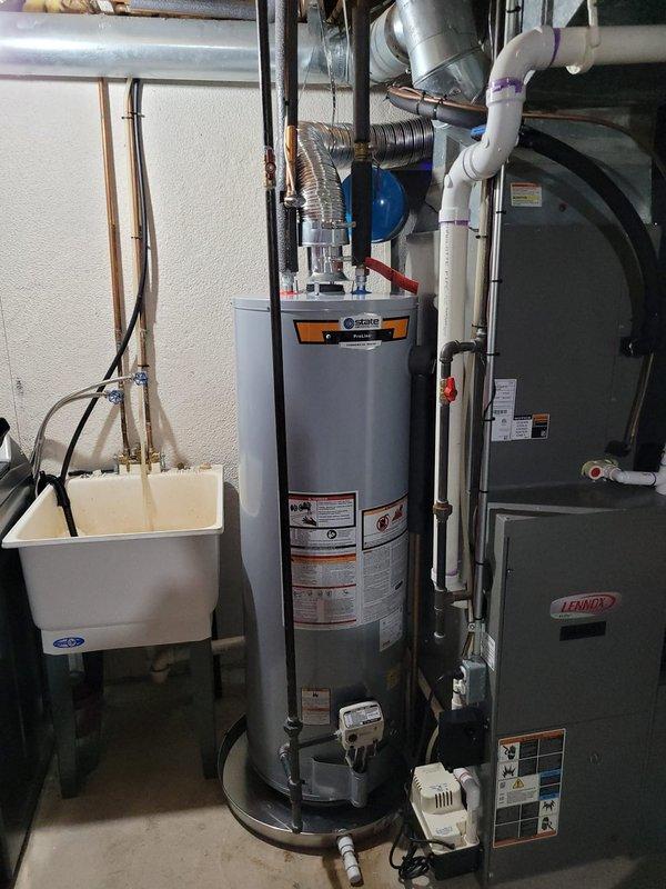 Completed installation of a 40-gallon natural gas water heater in residential utility room. Unit was installed with proper venting, gas line connections, cold water supply with expansion tank, and hot water distribution lines, meeting all code requirements and manufacturer specifications.