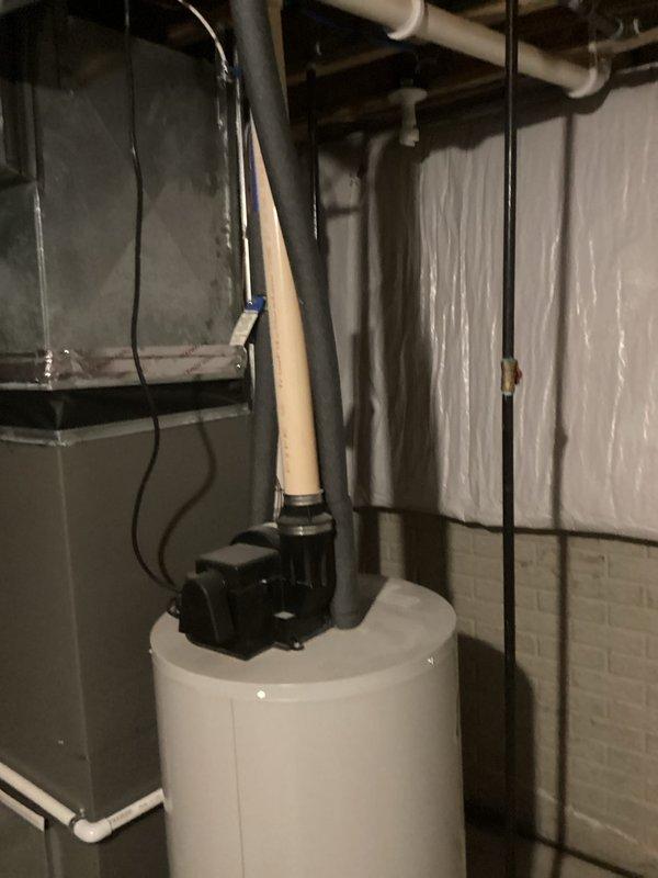 Completed estimate for hot water heater replacement in basement utility area. Assessed existing white cylindrical water heater with circulator pump mounted on top, evaluated current plumbing connections including both copper and PVC piping, and documented moisture staining on concrete floor around unit base. Provided customer with replacement options and specifications for new water heater installation.