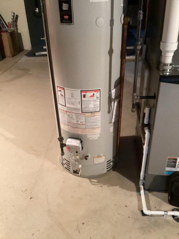 Conducted on-site assessment for water heater replacement in basement of 26-year-old residential property. Inspected existing gas-fired water heater installation, documenting current unit configuration, venting system with metallic flexible duct, copper supply piping with shutoff valves, and PVC drain connections. Evaluated utility room layout, clearances, and existing plumbing infrastructure to determine replacement specifications and installation requirements. Photographed equipment, piping connections, gas valve assembly, and surrounding HVAC components to prepare comprehensive replacement estimate.