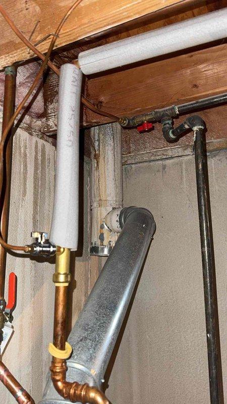 Responded to service call for leaking PVC condensate drain line from previous HVAC installation. Inspected plumbing connections in basement utility area and identified compromised drain line requiring repair or replacement to prevent water damage. Documented existing conditions including pressure vessel, copper supply lines, and associated plumbing components for service records.