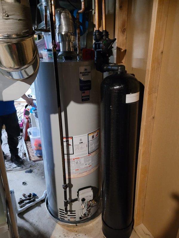 Completed installation of a 50-gallon Bradford White tanked water heater in residential utility space. Connected all copper supply and discharge piping, installed expansion tank, and integrated system with existing water treatment equipment. All plumbing connections were secured with proper fittings and valves, flexible ductwork was positioned for venting, and unit was tested for proper operation upon completion.