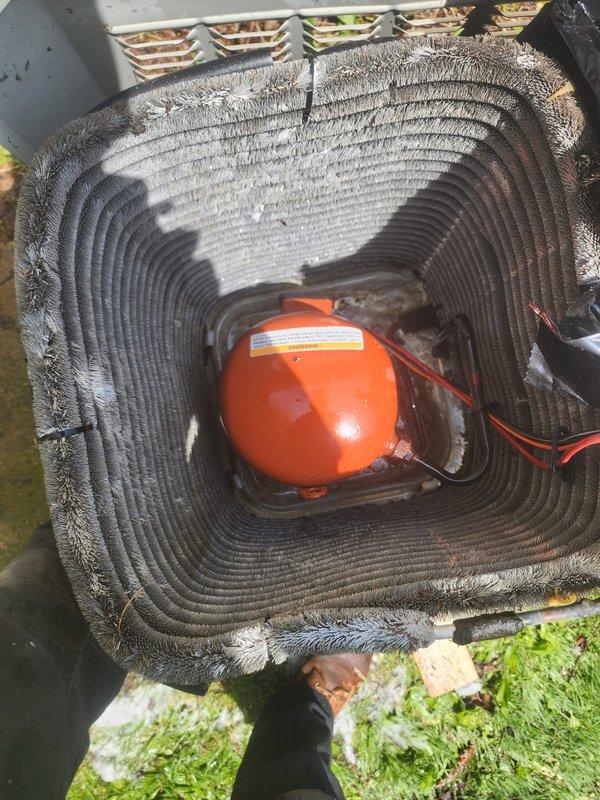 Completed comprehensive AC tune-up on outdoor condenser unit located in backyard. Performed standard maintenance protocol including inspection of evaporator coil assembly, which showed moderate dust accumulation on fins and presence of condensate safety switch (orange float device) functioning properly. Inspected condenser unit with horizontal fin configuration, verified refrigerant line connections and insulation integrity, and checked unit mounting on concrete pad. No operational issues identified during inspection; system components found in serviceable condition with typical environmental debris accumulation for outdoor installation.