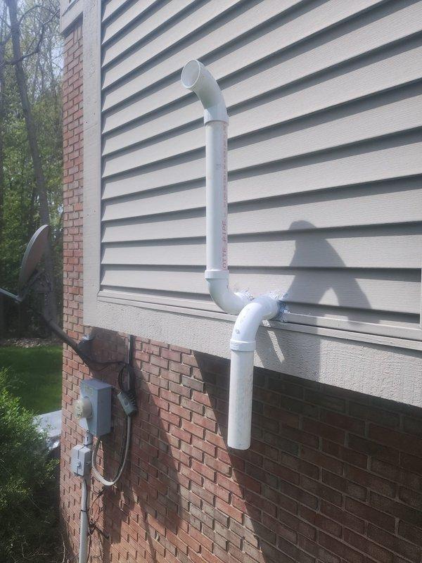 Responded to indoor air quality concerns regarding dry eyes and stomach issues when HVAC system operates. Inspected exterior ventilation terminations and PVC vent piping system for potential contamination or pest intrusion. Examined white louvered vent panel mounted on brick exterior wall and associated drainage/ventilation piping runs. No visible signs of pest infiltration, debris blockage, or compromised vent integrity observed during exterior inspection.