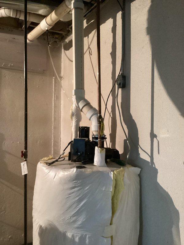 Conducted on-site assessment for water heater replacement in residential basement utility area. Evaluated existing water heater installation, surrounding plumbing infrastructure, and available space for new unit installation. Documented current equipment configuration including water softener system with associated PVC piping, overhead ductwork clearances, and electrical service routing. Photographed existing installation showing protective measures in place and equipment layout to facilitate accurate estimate preparation for complete water heater replacement.