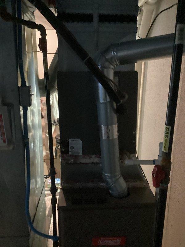 Conducted comprehensive site evaluation for complete HVAC system replacement at residential property. Assessed existing Coleman furnace unit, ductwork configuration, and current air filtration system in basement utility area. Documented equipment specifications, spatial constraints, and existing infrastructure including metallic supply ductwork with angular connections and wall-mounted air purification device. Evaluated furnace condition noting sealed horizontal seam with barrier tape, standard air intake with diamond lattice filter, and proper clearances within unfinished space. Photographed secondary mechanical area showing water heating equipment and dark ductwork distribution system with exposed framing and insulation. Compiled measurements and technical specifications necessary for preparing accurate replacement estimate including equipment sizing requirements, ductwork modifications, and installation logistics for proposed air conditioning system integration.