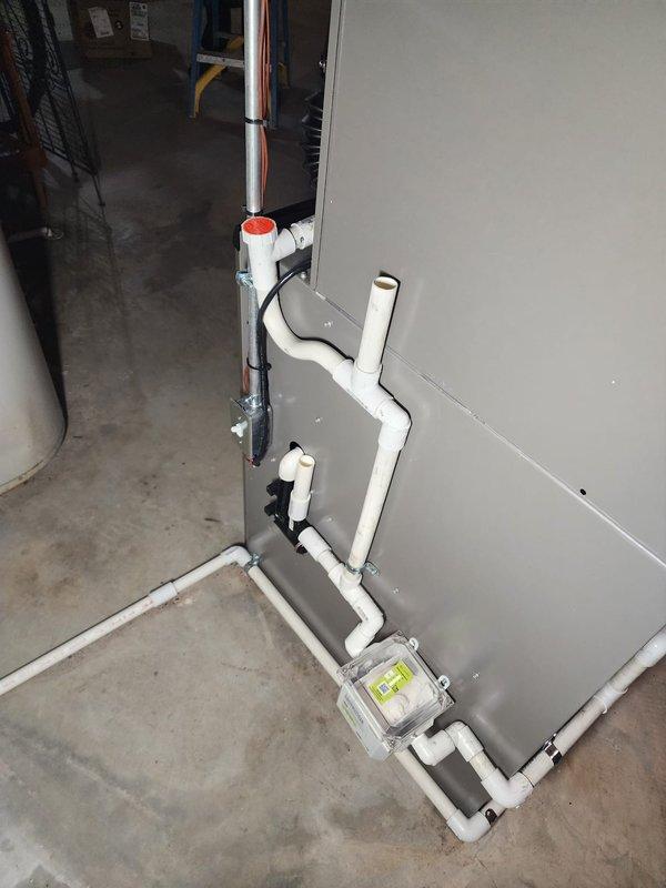 Completed full HVAC system installation including Lennox furnace, air conditioning unit, S40 smart thermostat, and whole-home humidifier in basement mechanical room. Installed new PVC condensate drainage system with pump assembly and trap, configured supply and return ductwork connections, and ran copper refrigerant lines from outdoor condenser to indoor air handler. All equipment tested and operational, thermostat programmed, and humidifier plumbed to furnace with proper water supply connection.