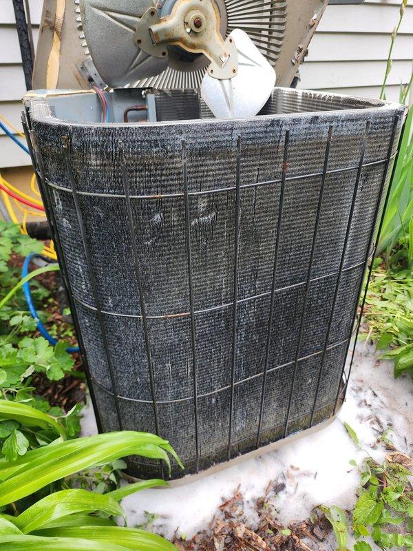 Completed comprehensive tune-up service on residential air conditioning system. Removed top panel to access internal components and performed thorough inspection of condenser unit. Condenser coils exhibited heavy accumulation of dirt, dust, and outdoor debris, which was cleaned to restore optimal heat transfer efficiency. Inspected fan motor assembly, fan blades, and electrical connections; all components found to be operational. Cleared organic debris from concrete pad and surrounding area. System tested and confirmed operating within normal parameters upon completion.