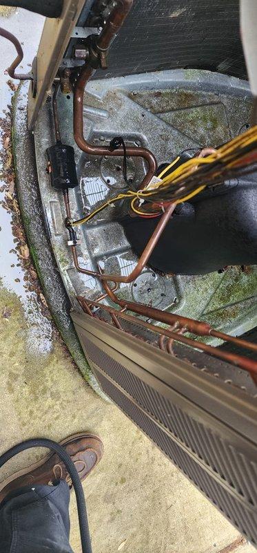 Completed preventive maintenance inspection on Lennox outdoor condensing unit. Unit exhibited significant biological growth including moss and algae accumulation on interior framework, panels, and support structures, along with debris buildup in condenser coil fins and base area. Documented existing conditions showing environmental exposure, oxidation on copper refrigerant lines, and organic matter accumulation requiring attention to maintain optimal system performance and efficiency.