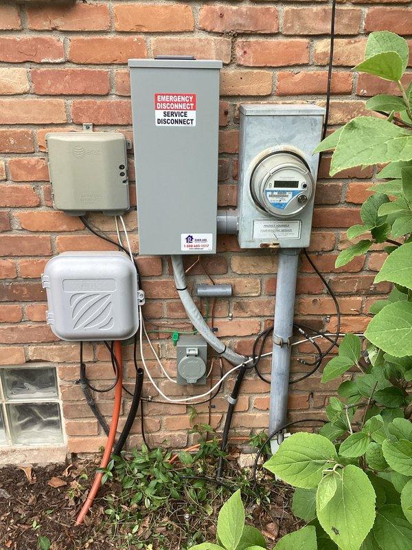 Removed obsolete GE split buss panel and replaced with new 200-amp Leviton load center equipped with smart breaker capability for future load monitoring upgrades. Installed exterior 200-amp emergency disconnect switch and whole house surge suppressor to meet current electrical code requirements. Upgraded grounding and bonding system including cold water ground, intersystem bonding bridge, and ground rod installation per NEC standards.

Removed existing AC interruptible meter base and integrated AC circuit directly into new panel. Replaced aluminum branch circuit wiring with copper conductors for EV charger receptacle and installed GFCI breaker protection. Added GFCI breaker protection for spa circuit. Installed mechanical interlock system with 30-amp generator inlet on exterior wall adjacent to utility meter, enabling portable generator backup capability during power outages. Completed full circuit identification and labeling of panel directory. All work performed under permit with fin
