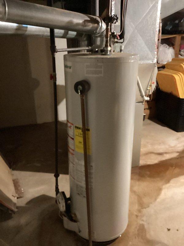 Provided estimate for replacement of 10-year-old residential water heater with larger gallon capacity located in basement utility area. Assessed existing unit with standard copper piping connections and proper venting, documented current installation conditions including exposed ductwork and mechanical systems in unfinished basement space.