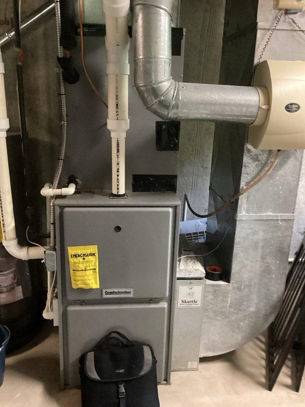 Completed air conditioning replacement estimate for residential property. Assessed existing furnace installation in basement utility area, including gray metal furnace unit with associated ductwork, PVC drainage and venting systems, and surrounding mechanical components. Documented current HVAC system configuration, ductwork layout with metallic elbow joints, white PVC piping for condensate drainage, copper tubing, and flexible conduit installations. Evaluated equipment placement, accessibility for future replacement, and compatibility with existing infrastructure including water heater proximity and Skuttle humidifier integration. Photographed mechanical room setup to provide comprehensive documentation for replacement system specifications and installation planning.