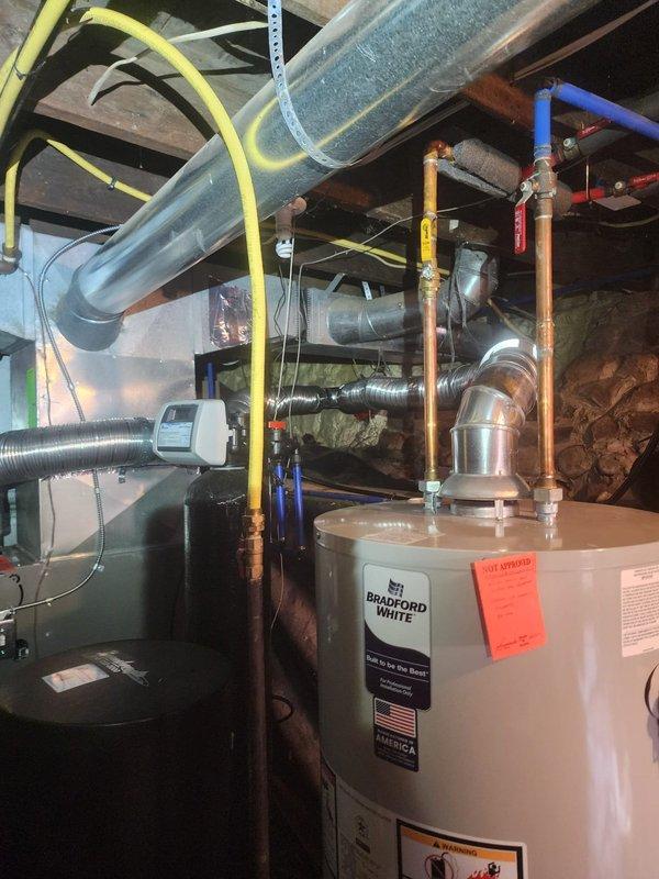 Responded to callback for water heater drafting issue. Upon inspection, determined existing unit required replacement due to improper venting conditions. Removed old water heater and installed new Bradford White 40-gallon short residential gas water heater. Connected all copper supply and distribution lines, installed temperature and pressure relief valve, and ran new yellow CSST gas line to unit. Verified proper draft operation through existing ductwork system, tested all connections for leaks, and confirmed hot water delivery throughout the home. Documented installation with photographs showing completed water heater setup, proper venting configuration through basement ductwork, and all plumbing connections. Unit operational and drafting properly upon departure.