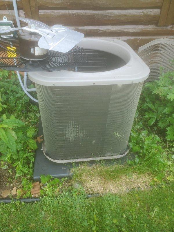 Completed routine AC maintenance on residential split-system cooling unit. Inspected outdoor condenser unit positioned on composite pad adjacent to building structure, verified proper clearances and airflow around cabinet, and confirmed white PVC refrigerant lines and electrical conduit connections were secure. Examined interior evaporator coil assembly and drain pan for proper operation, noting active condensation present indicating system was cycling normally. Observed moisture accumulation in black plastic drain pan with visible water droplets on surfaces, confirmed drainage pathways were clear, and verified copper refrigerant lines showed no signs of damage or refrigerant leakage. Checked evaporator coil fins for debris accumulation and airflow restrictions. All components inspected and found to be operating within normal parameters for continued reliable cooling performance.