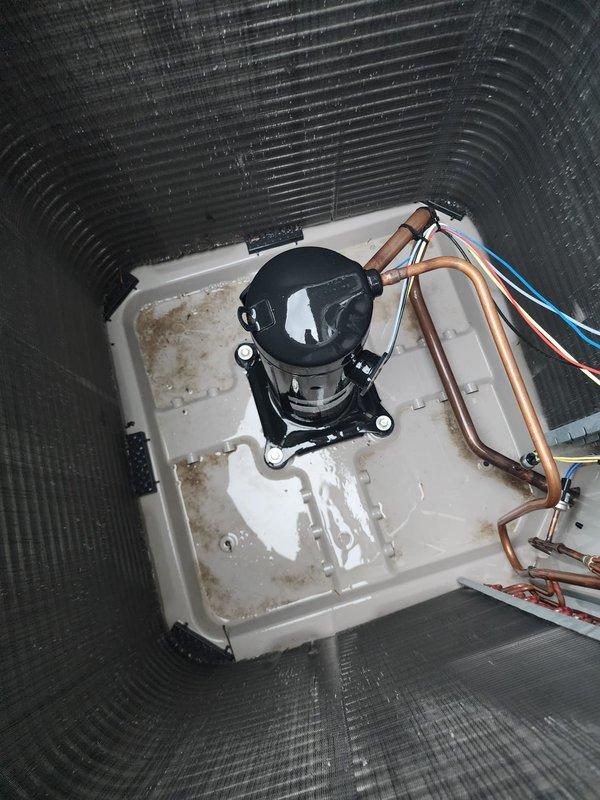 Completed routine maintenance on 3-5 ton air conditioning system including inspection of evaporator coil assembly and compressor unit. Photographically documented clean condenser fins, properly functioning compressor with refrigerant lines, and drain pan condition showing normal condensate staining, confirming system is operating within manufacturer specifications.