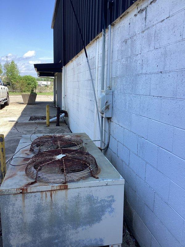 Completed estimate for HVAC system replacement at commercial facility where existing air conditioning unit had been previously removed. Assessed platform location above office area and evaluated installation requirements for new condensing unit on side of building. Documented existing deteriorated equipment showing extensive rust damage, weathered components, and corroded mounting hardware requiring complete system replacement.