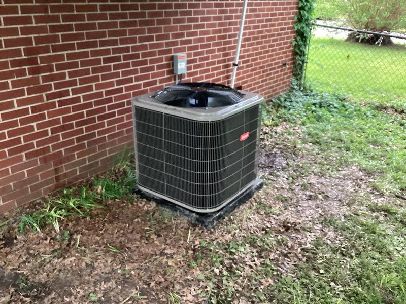 Completed installation of new Bryant air conditioning condenser unit at residential property. Mounted unit on composite base pad against exterior brick wall in side yard location. Installed electrical disconnect box on brick wall above unit with proper conduit routing. Ran refrigerant lines with black foam insulation from condenser up exterior wall, securing lines with appropriate fittings and service ports. Installed condensate pump with discharge line routed to exterior per sales specifications. Verified all electrical connections, tested system operation, and confirmed proper refrigerant charge levels.