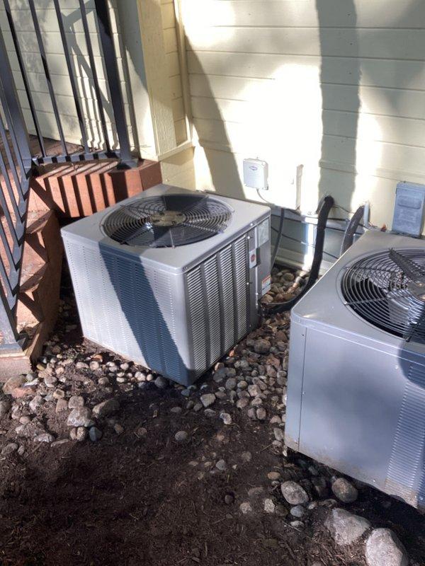 Conducted HVAC estimate for air conditioning replacement at residential property with two outdoor condenser units positioned against exterior wall on gravel base. Upon inspection, discovered one unit was low on refrigerant. Recharged the system with appropriate refrigerant to restore proper operating levels. Documented existing dual-unit installation including positioning relative to gas meter infrastructure and building utilities for replacement planning purposes.