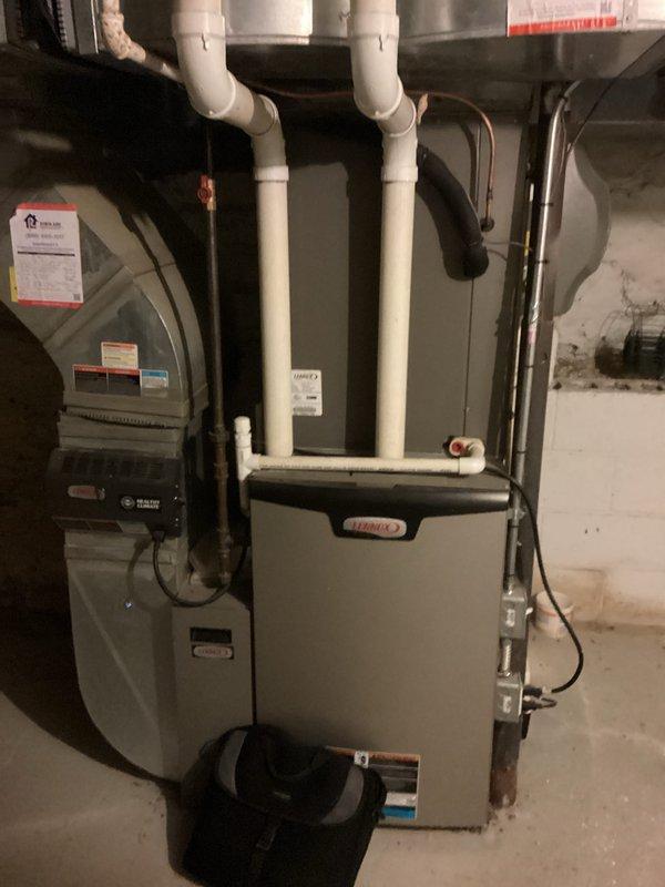 Technician diagnosed a failed condenser motor on an 11-year-old air conditioning system. Upon evaluation of the aging equipment and repair costs, provided estimate for complete HVAC system replacement. Assessment included inspection of existing furnace and air handler configuration in basement mechanical room, review of current installation with PVC condensate drainage, flexible ductwork connections, and refrigerant line routing. Replacement estimate prepared to address failed component and account for system age and overall condition.