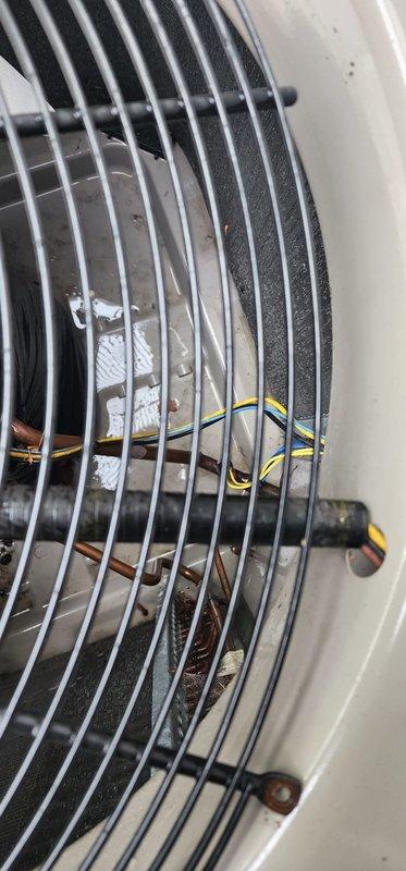 Completed scheduled A/C maintenance on outdoor condensing unit. Performed visual inspection of fan assembly through protective grille, confirming proper blade condition and electrical connections. Unit exterior and surrounding area show normal outdoor weathering with minimal debris accumulation; system operational and ready for cooling season.