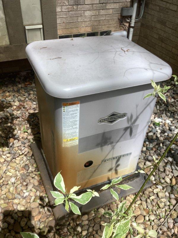 Completed routine generator maintenance inspection and service. Performed visual inspection of outdoor generator unit, noting weathered condition with surface oxidation on housing and lid. Verified unit accessibility and cleared vegetation growth around base perimeter. Conducted standard preventive maintenance procedures including mechanical assessment and component verification using appropriate hand tools and socket attachments. Unit operational following maintenance completion.