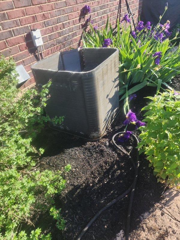 Completed seasonal AC maintenance inspection on residential condensing unit. Performed visual inspection of outdoor unit positioned in landscaped area, verified electrical connections at compressor assembly, and assessed overall system condition including copper compressor component and mounting base. Unit operational with no immediate service concerns identified during maintenance visit.