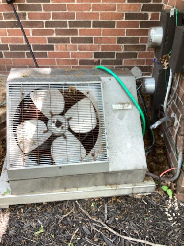 Provided estimate for complete air conditioning system replacement at condo unit with outdoor installation on back patio. Existing equipment dating from 1970 is non-operational, showing extensive corrosion, rust on fan assembly, and significant weathering throughout the unit. Assessed installation area including electrical service, meter configuration, disconnect switch, refrigerant line routing, and concrete pad condition to determine replacement specifications and equipment requirements.