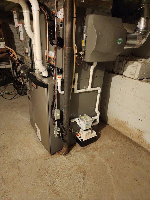 Completed full HVAC system installation in residential basement utility room. Installed new Lennox high-efficiency furnace with matching air conditioning system and S40 smart thermostat. Ran white PVC venting and condensate drain lines from furnace unit through existing ductwork penetrations. Connected refrigerant lines between outdoor condensing unit and indoor evaporator coil. Mounted condensate pump on platform at base of installation to ensure proper drainage. Integrated air handler section with existing metal ductwork system and verified all connections secure. Completed electrical wiring to furnace, air handler, and control components per manufacturer specifications. Installed and programmed S40 thermostat for optimal system performance. Tested all safety controls, verified proper airflow through supply and return ducts, and confirmed system operation in both heating and cooling modes. All equipment operational and performing to manufacturer standards upon completion.