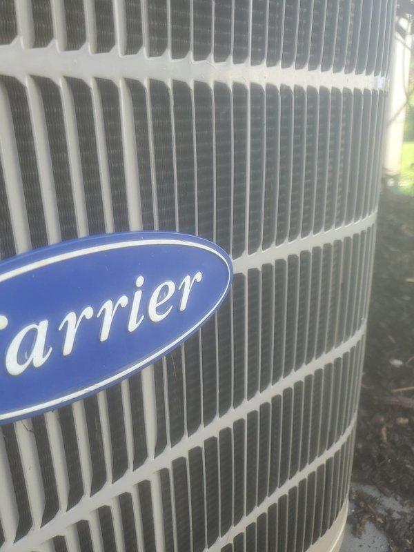 Completed routine air conditioning maintenance on Carrier outdoor condensing unit. Performed system inspection, verified proper operation of condenser coil and refrigeration lines, and documented equipment condition with interior and exterior components showing normal moisture levels consistent with active cooling cycle.