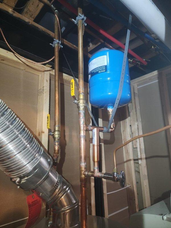 Responded to warranty call for water heater installation issues. Addressed leak at cold water inlet connection showing rust-colored staining around brass fitting and corrected improper expansion tank mounting to comply with manufacturer installation specifications. Documented completed repairs with photographs per protocol.