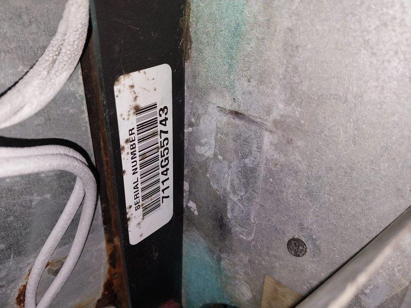# HVAC Service Call - No Cooling Condition

Responded to service call for residential heat pump system reporting no cooling operation. Upon arrival, performed visual inspection of outdoor condensing unit installed on exterior wall with river rock landscaping base. Unit exhibited signs of age with visible corrosion on mounting brackets and oxidation on metal surfaces consistent with 10+ year service life.

Conducted diagnostic evaluation of electrical connections and control components. Observed multiple conductor wiring entering unit through side panel with proper conduit installation. Serial number documented from equipment nameplate for service records. Noted accumulation of organic debris including leaves and pine needles around unit base which can restrict airflow and reduce system efficiency.

Assessed overall system condition including condensing coil fins, electrical terminations, and refrigerant line connections. Unit displayed typical wear patterns associated with extended out