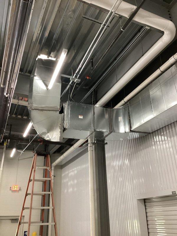 Responded to commercial furnace service call to address dented exhaust ductwork in bay area. Upon arrival, accessed ceiling-mounted HVAC system and inspected the damaged exhaust duct section connected to the furnace unit. Documented existing conditions with photographs showing the metallic ductwork configuration and surrounding mechanical infrastructure. Confirmed extended service window was utilized to complete thorough assessment of the exhaust system and ensure proper documentation of the damage for repair recommendations.