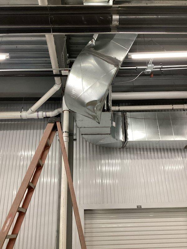 Responded to commercial furnace service call to address dented exhaust ductwork in bay area. Upon arrival, accessed ceiling-mounted HVAC system and inspected the damaged exhaust duct section connected to the furnace unit. Documented existing conditions with photographs showing the metallic ductwork configuration and surrounding mechanical infrastructure. Confirmed extended service window was utilized to complete thorough assessment of the exhaust system and ensure proper documentation of the damage for repair recommendations.