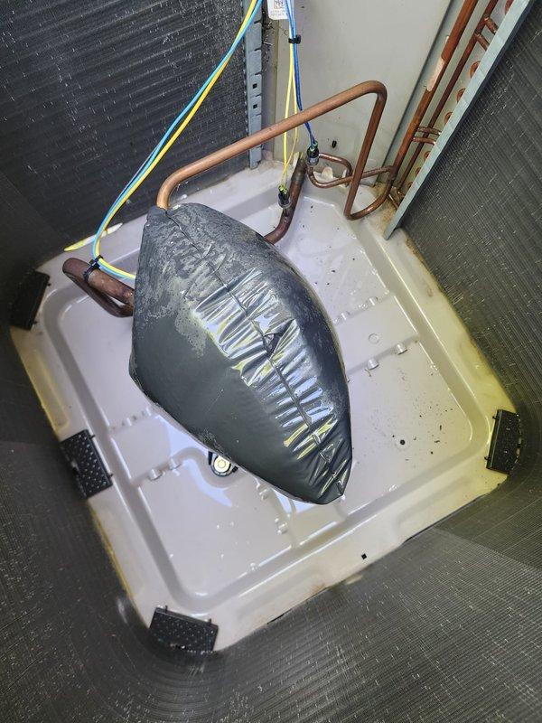 Completed comprehensive cooling system maintenance and tune-up on residential air conditioning unit. Performed standard preventive maintenance procedures including inspection of outdoor condenser unit with green side panels, verified proper operation of all components, and conducted drain system testing using inflatable bladder method in condensate pan. System tested and confirmed operational with all refrigerant lines, electrical connections, and coil assemblies functioning within normal parameters.