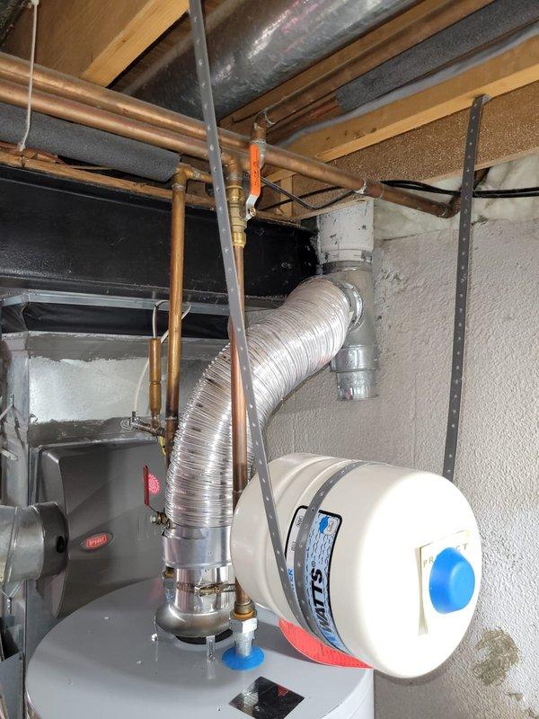 Replaced residential hot water heater and expansion tank in basement utility area. Corrected venting configuration by shortening ductwork to eliminate negative pitch and ensure proper draft. Completed all plumbing connections including copper supply lines and discharge piping. Removed old water heater from premises and transported to shop for disposal. System tested and operational upon completion.