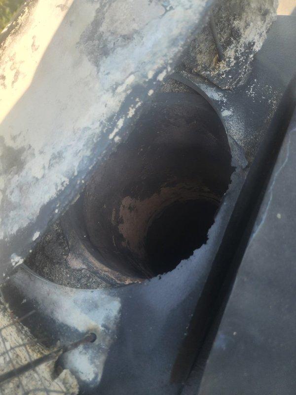 Responded to service call for displaced chimney cap and chimney liner condition assessment. Performed visual inspection of chimney penetration at roof level, documenting significant weathering and mineral efflorescence around the flue opening indicating moisture infiltration. Inspected water heater venting system and flue connection in mechanical room to verify proper draft and clearances. Provided customer with photographic documentation of chimney condition and recommendations for cap replacement and further liner evaluation.